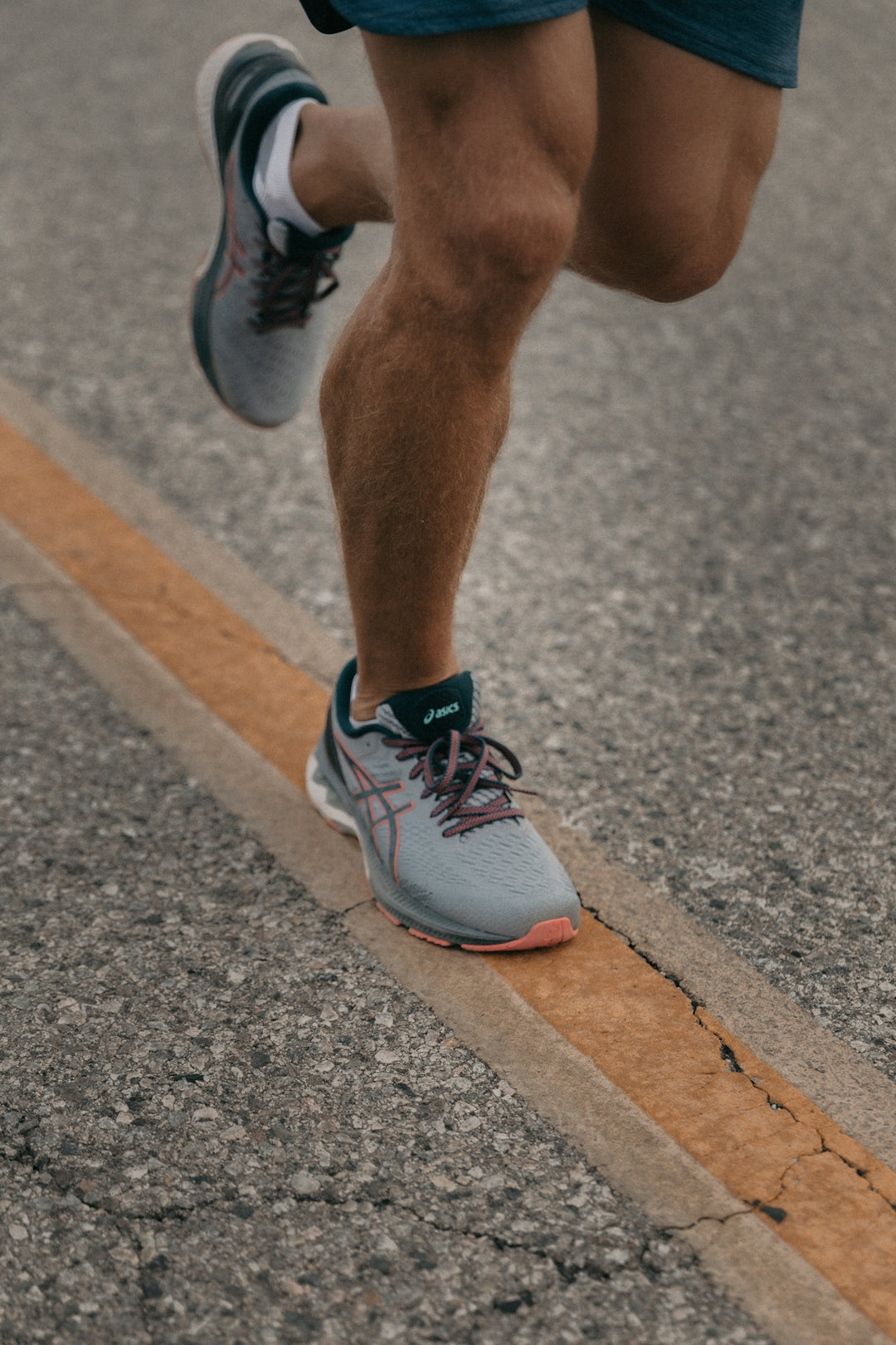 person running in gray asics sneakers