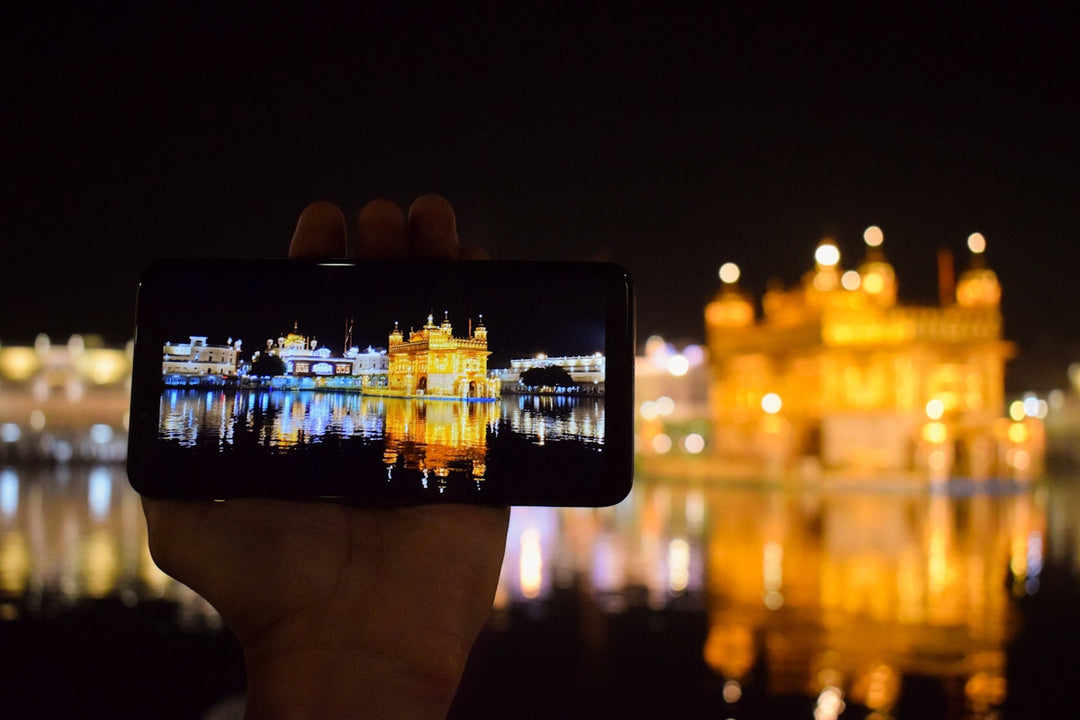 person holding smartphone taking photo of city buildings during night time