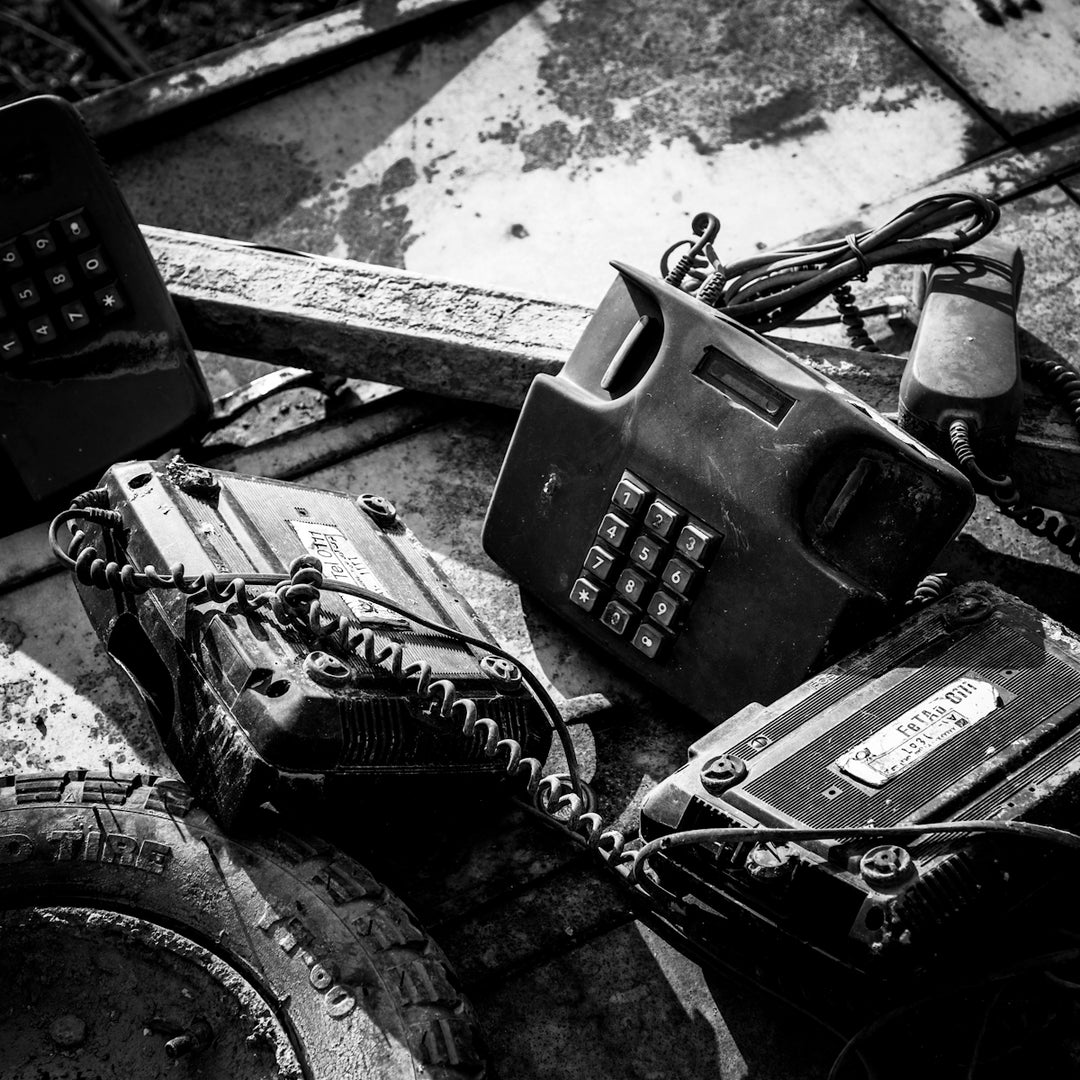 grayscale photo of telephone on wooden table