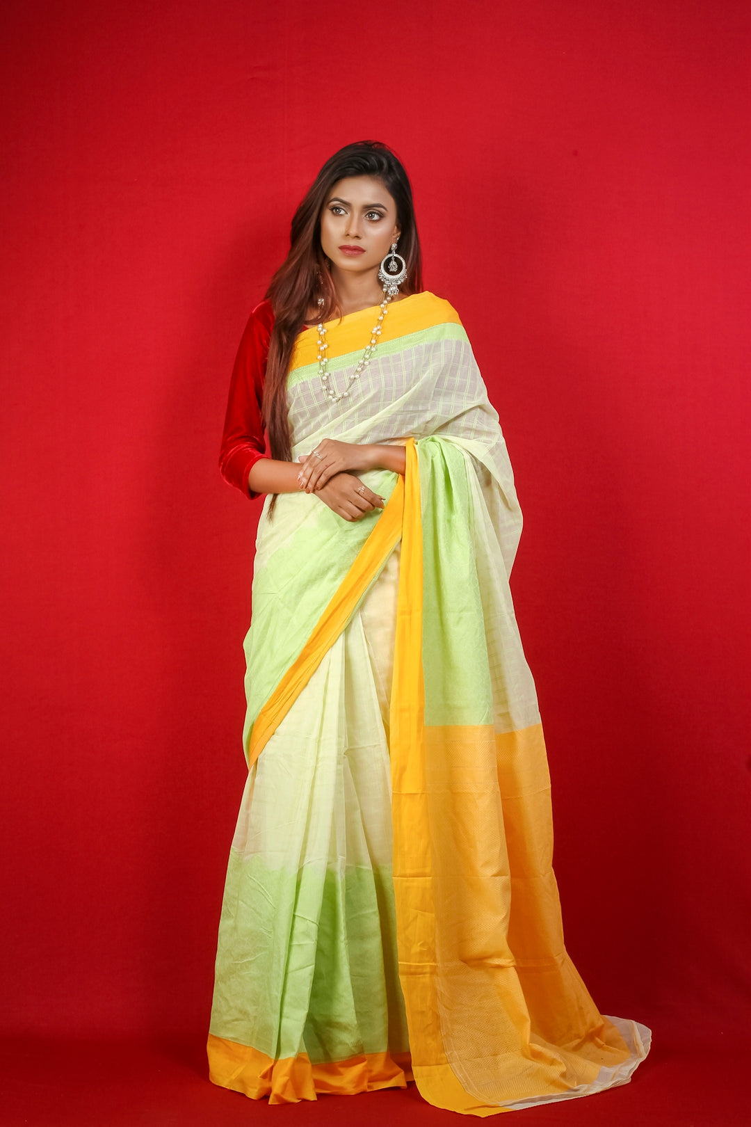 woman in red and yellow sari standing beside red wall