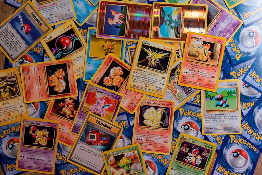 A collection of colorful Pokemon trading cards scattered across a flat surface
