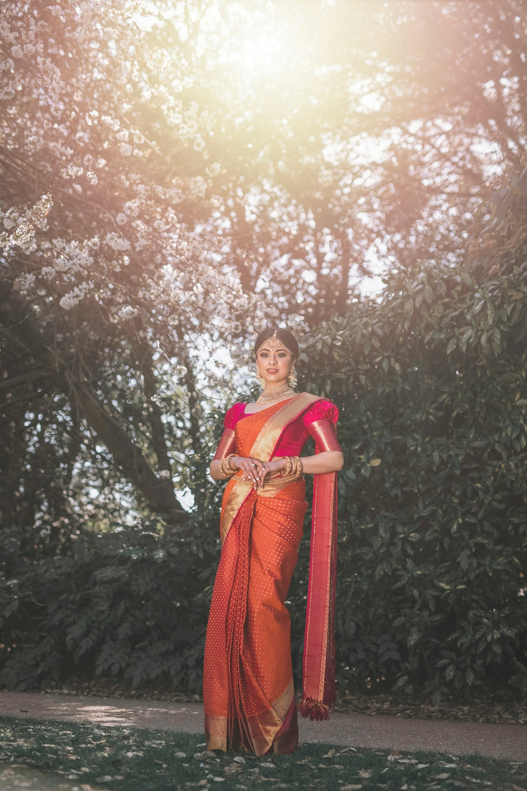 woman in red and brown sari standing under brown tree during daytime
