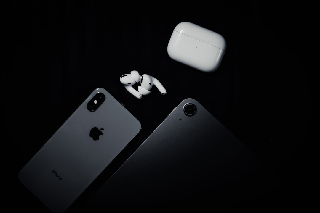 an iphone, ear buds, and an airpods sitting next to each other