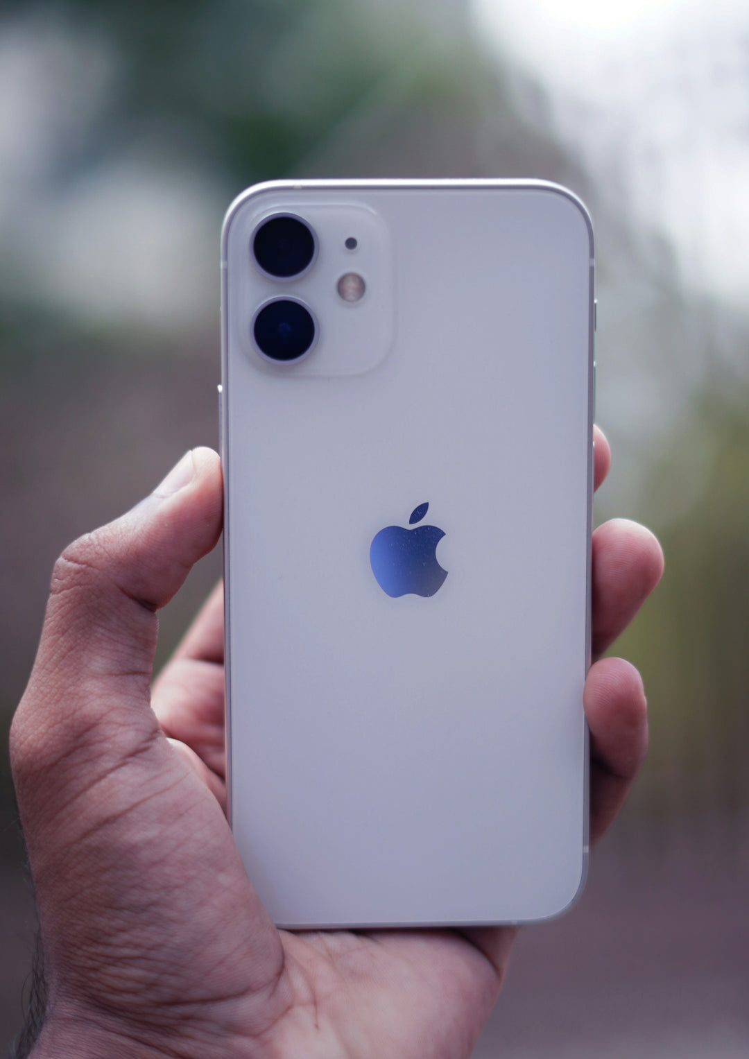 a hand holding a white cell phone
