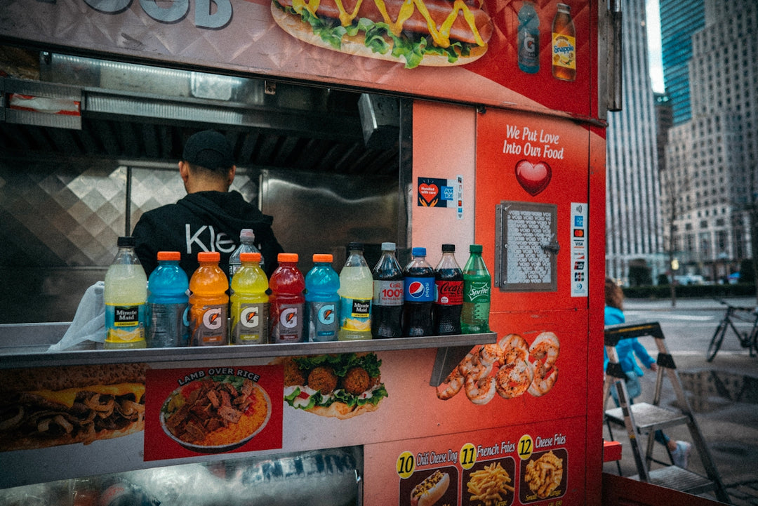 a man standing behind a food truck selling food