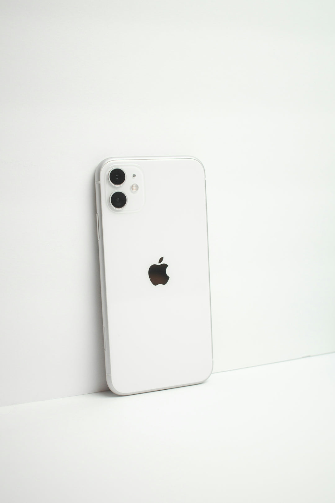 a white iphone sitting next to a white wall