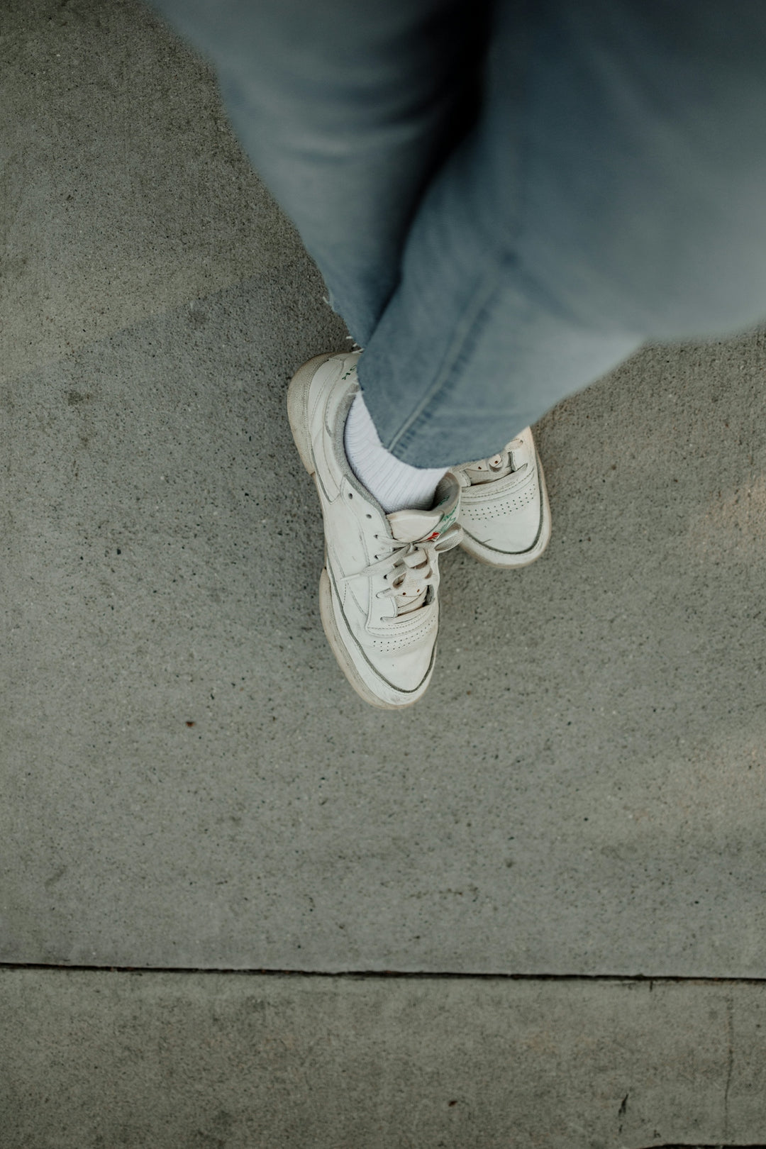 a person standing on a sidewalk wearing white shoes