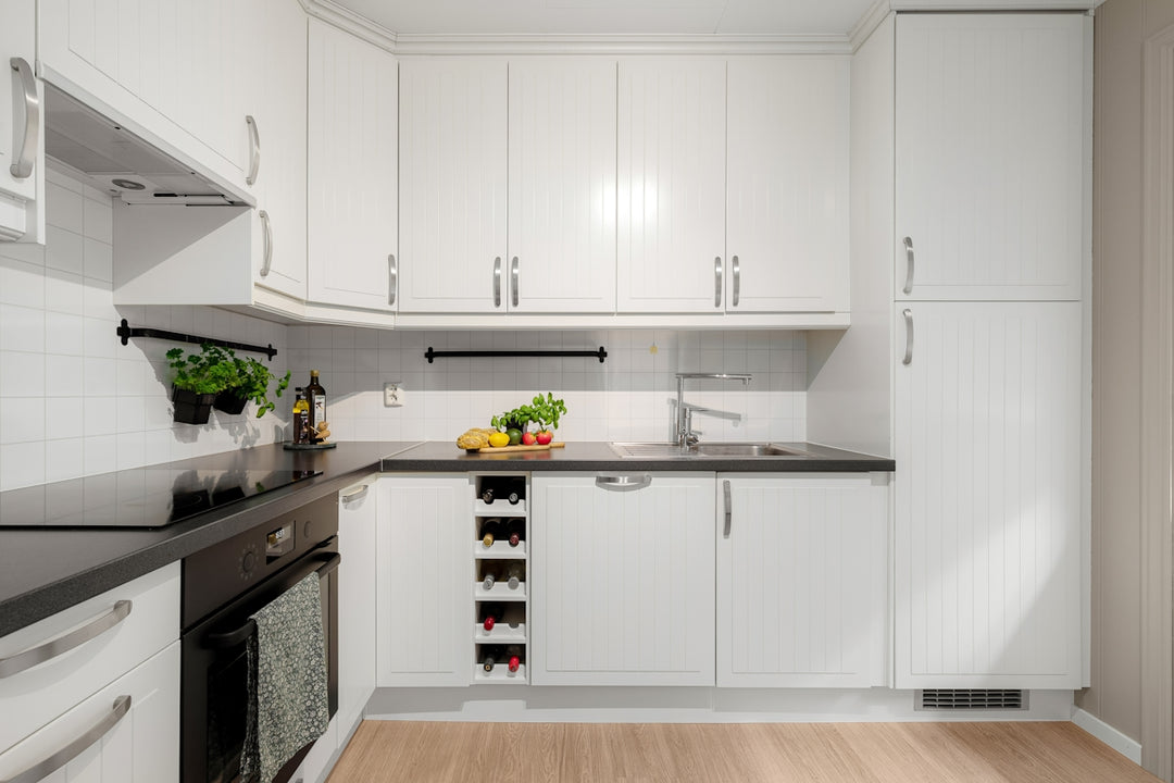 A kitchen with white cabinets and black counter tops