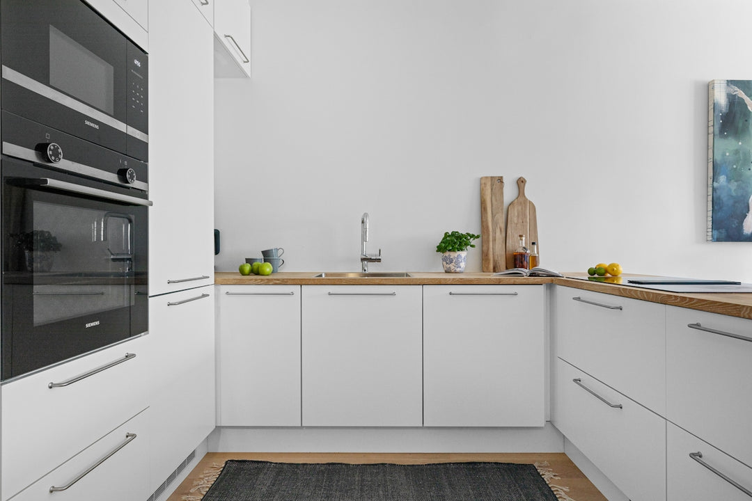 A kitchen with white cabinets and a wood floor