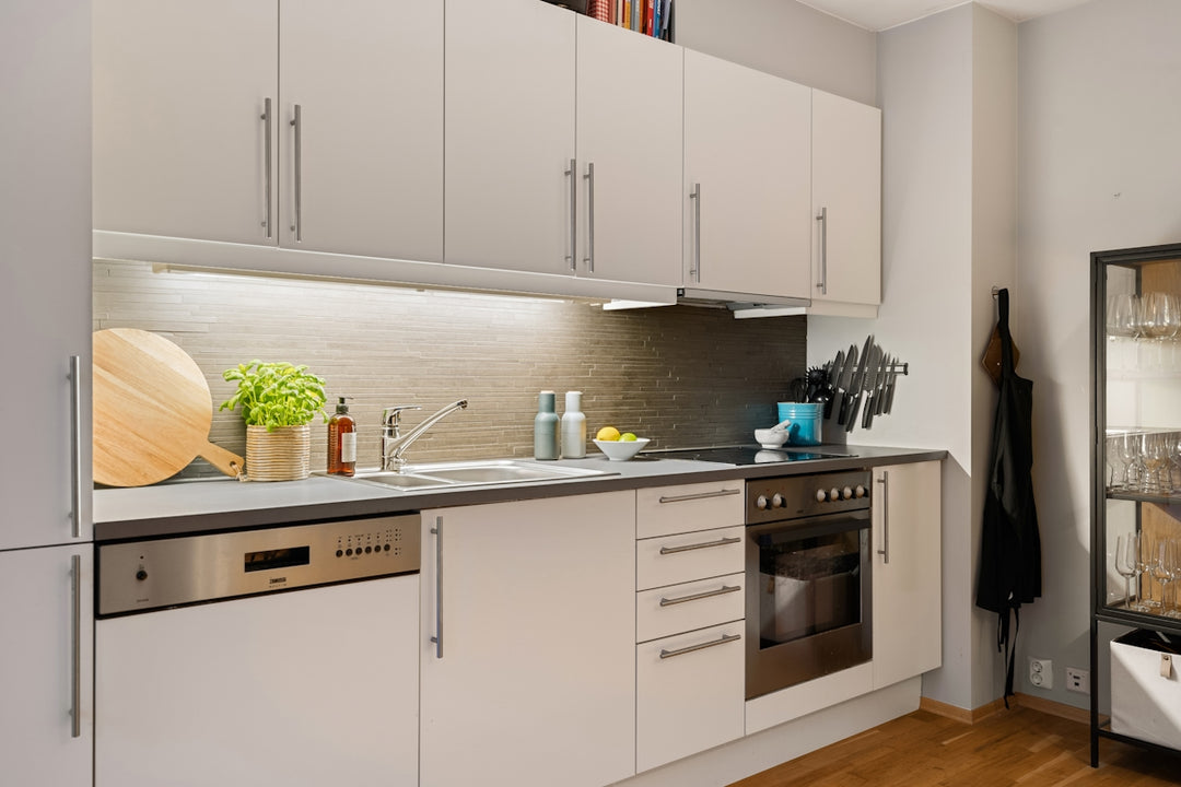 A kitchen with white cabinets and wood floors
