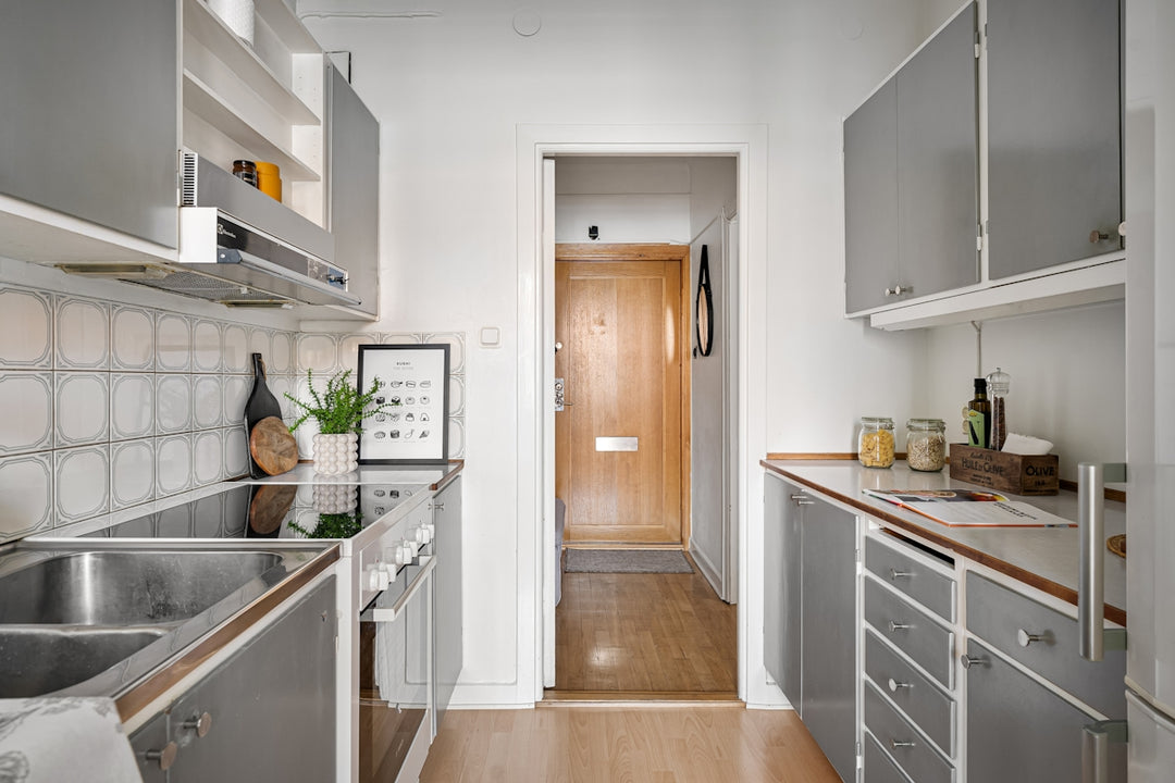 A narrow kitchen with stainless steel appliances and wood flooring