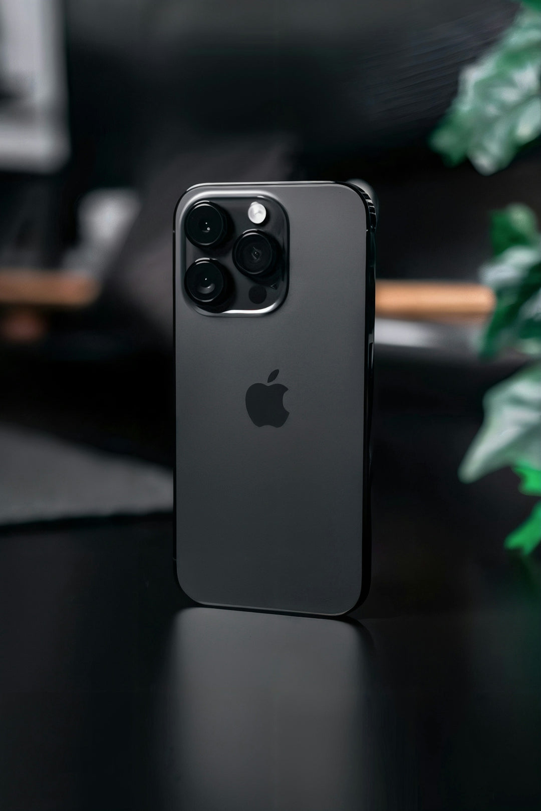 An iPhone 11 pro sitting on a table next to a plant