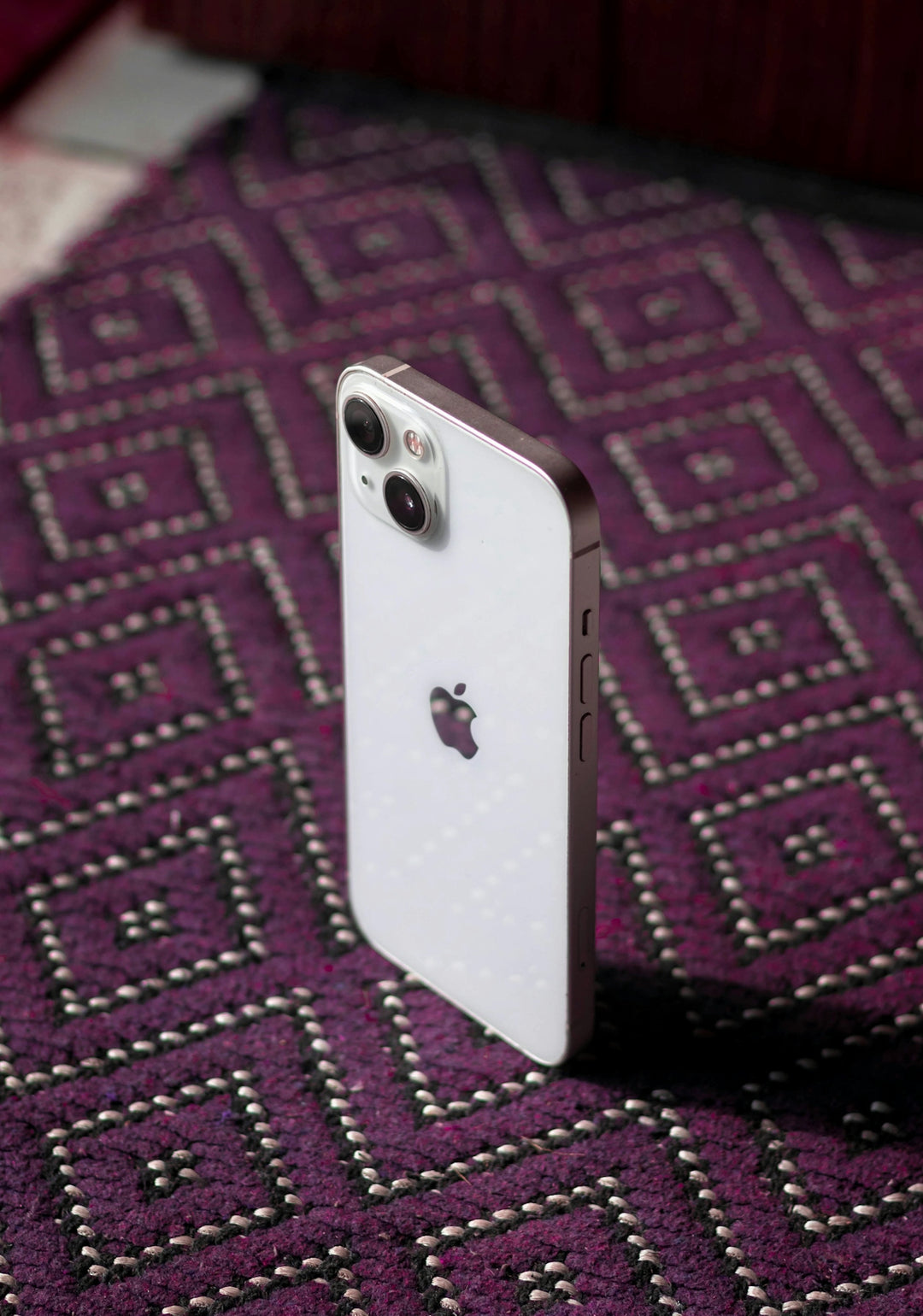 An iPhone is laying on a purple carpet