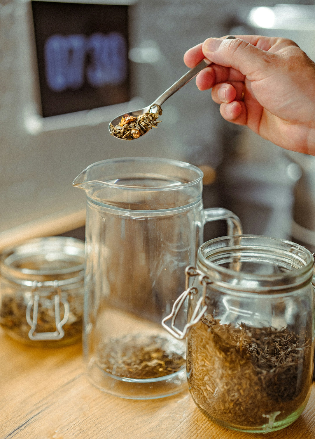 A person holding a spoon over a jar of food