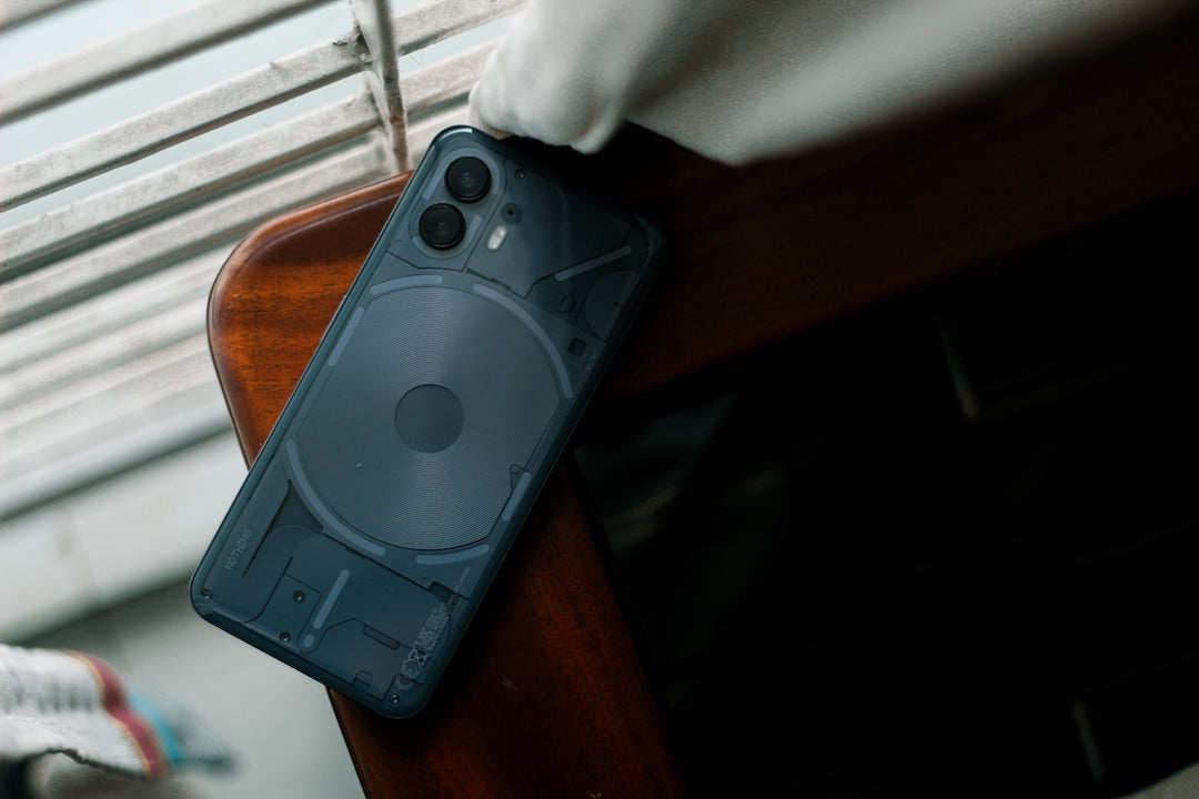 A modern smartphone rests on a wooden surface.
