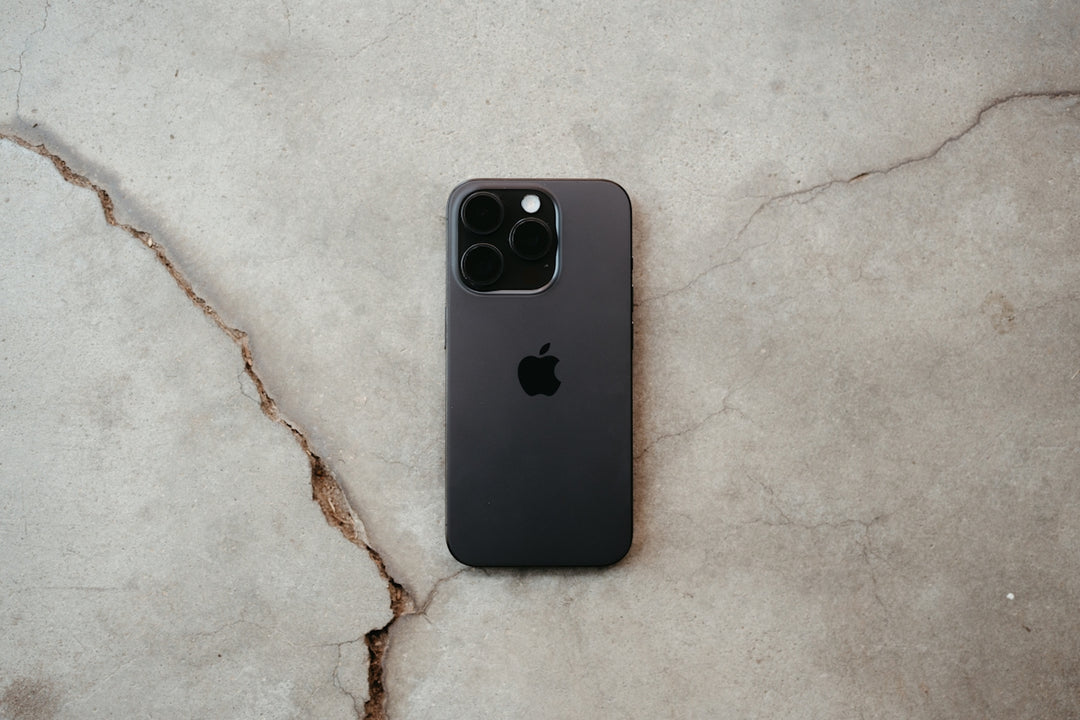 An apple iPhone is on a cracked surface.