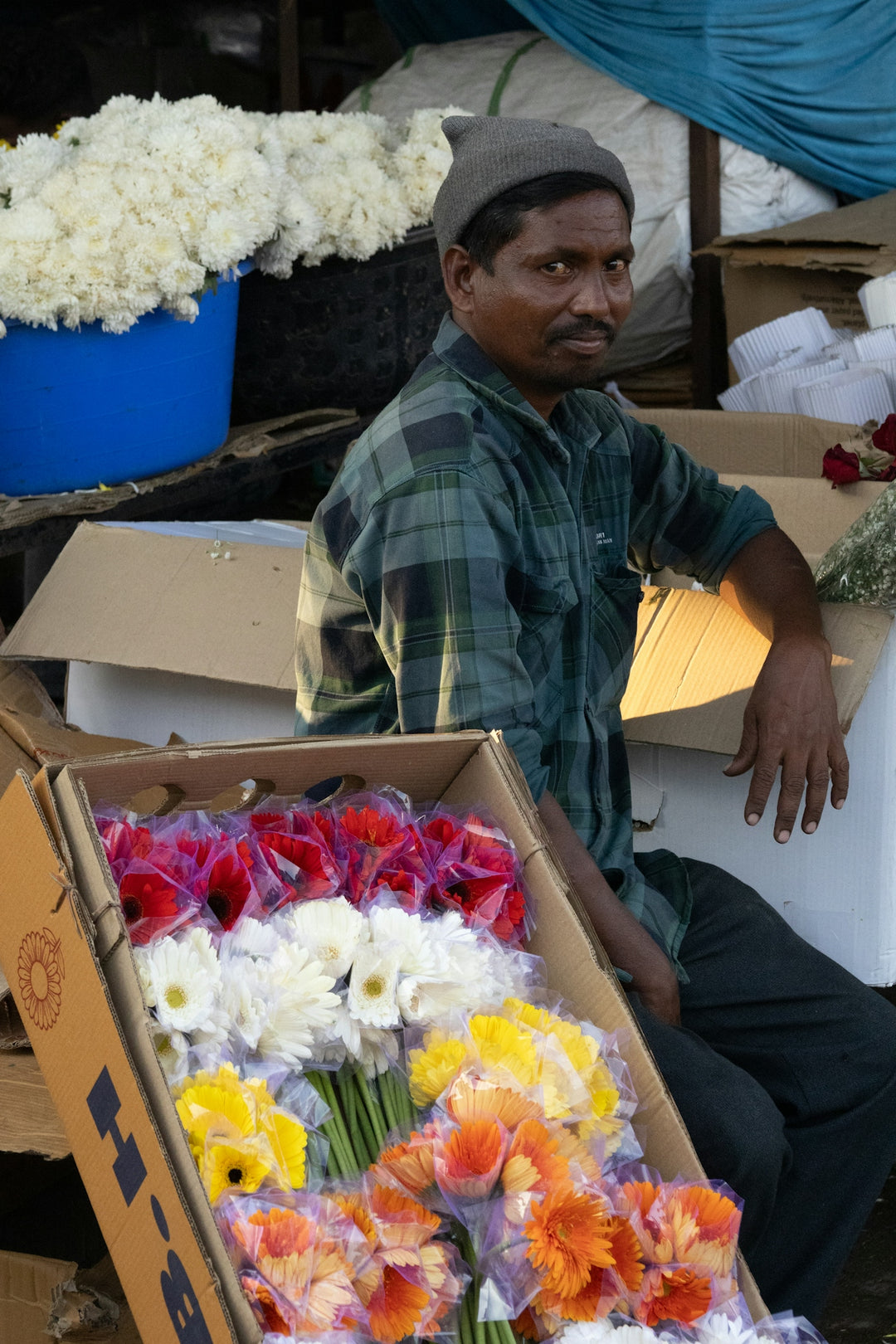 A flower vendor poses with his colorful flowers.