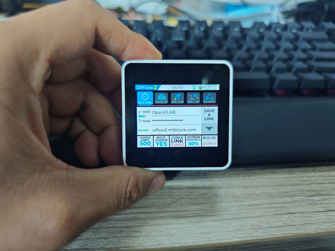 A hand holds a small device showing data.