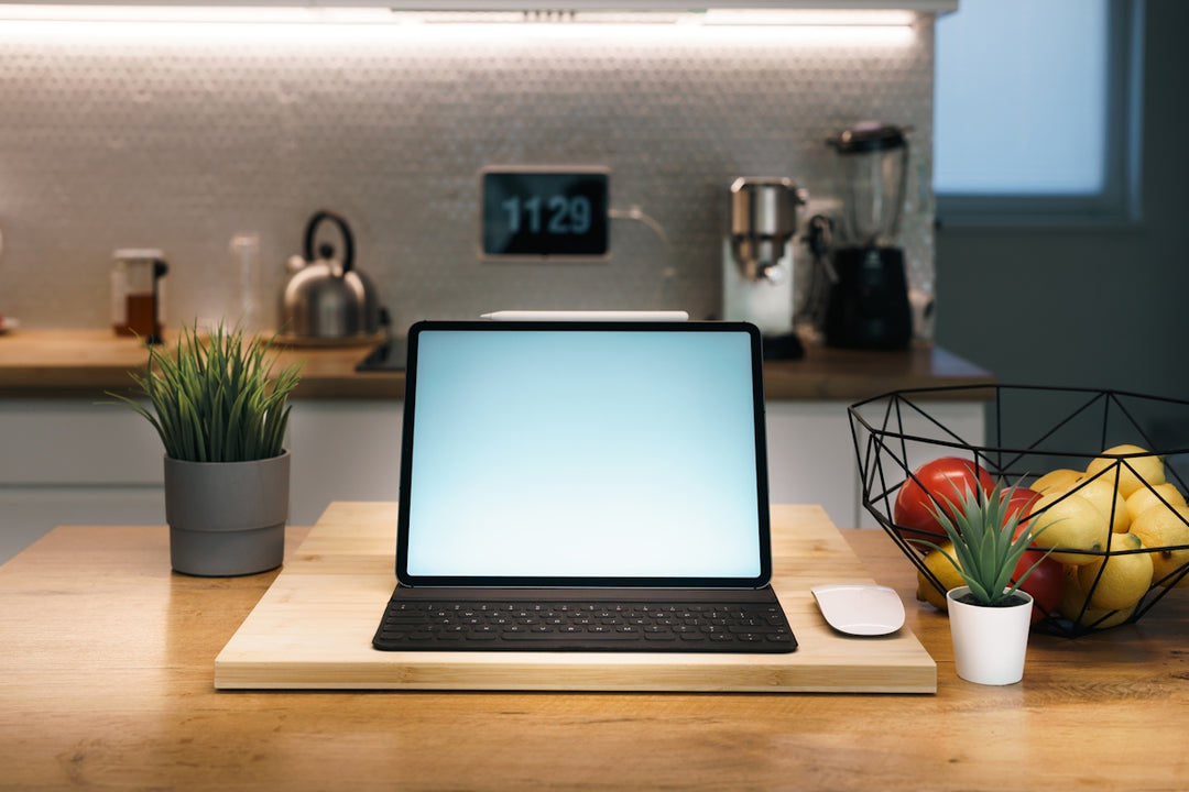 Laptop, mouse, and fruit on a kitchen counter.