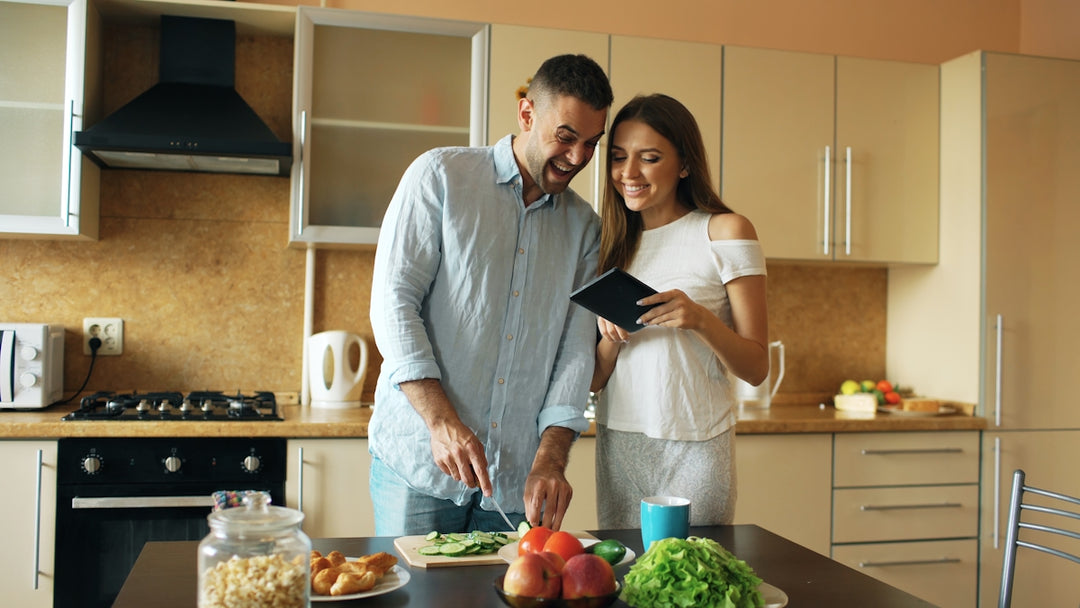Couple smiling while preparing food in kitchen