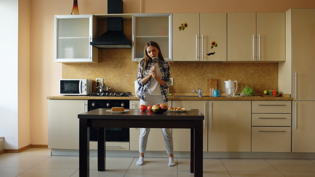 Young woman standing in a kitchen with apples on table.