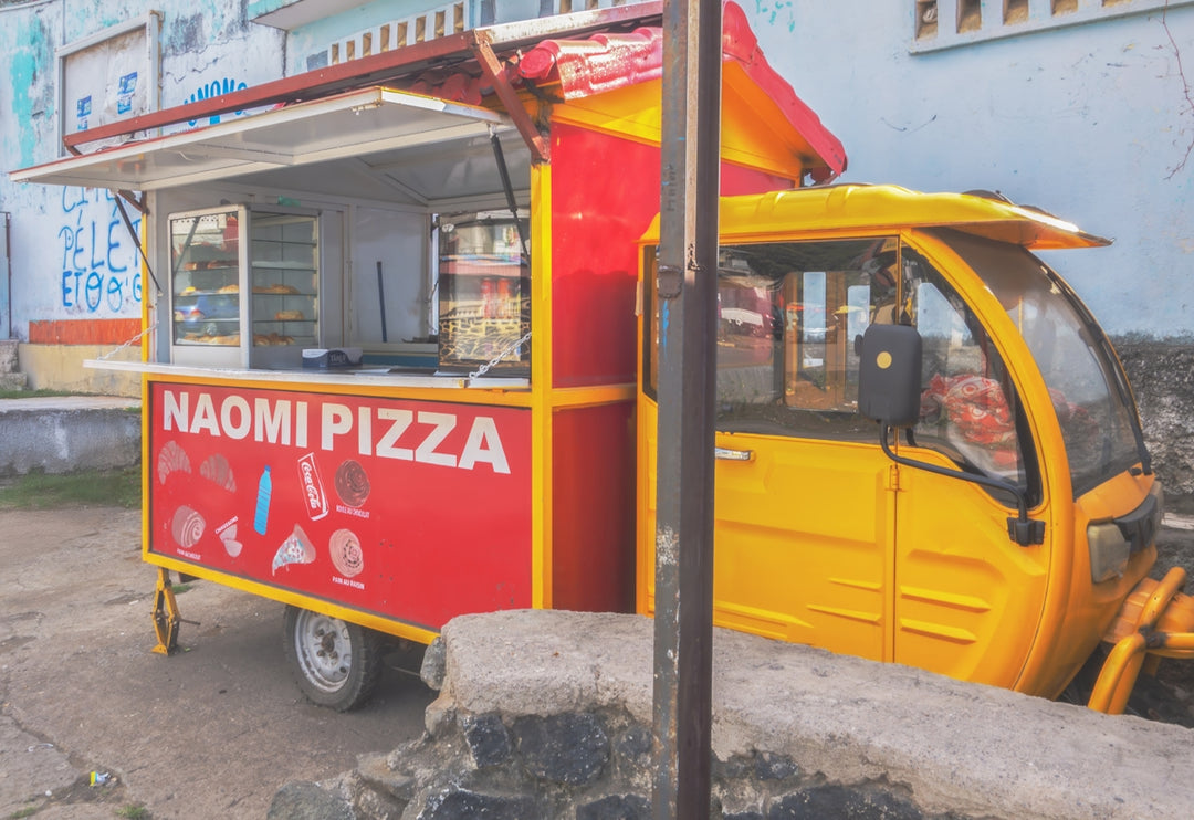 A yellow food truck selling pizza