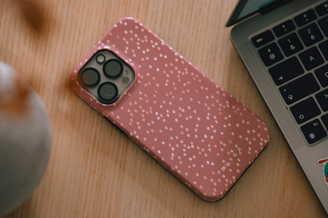 Pink speckled phone case next to laptop