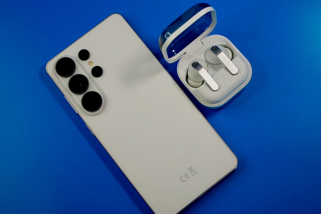 White smartphone and wireless earbuds on blue background