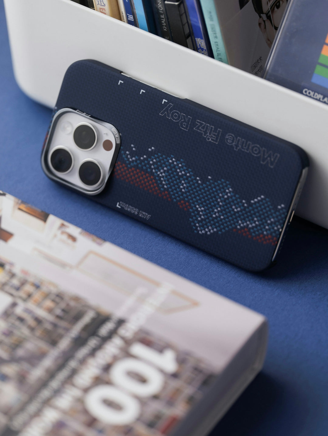 Navy iPhone with unique patterned case next to magazine.