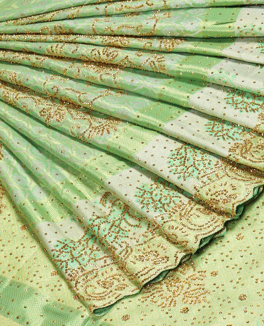 Green silk saree of ogee design with stonework, self curve border of peacock design & grand pallu embedded with stones